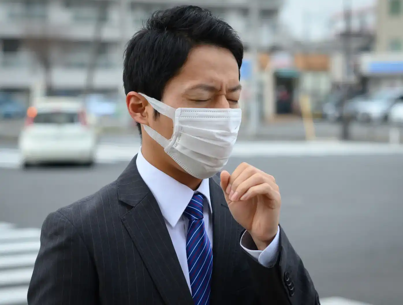 マスクを着けて咳をする男性のイメージ