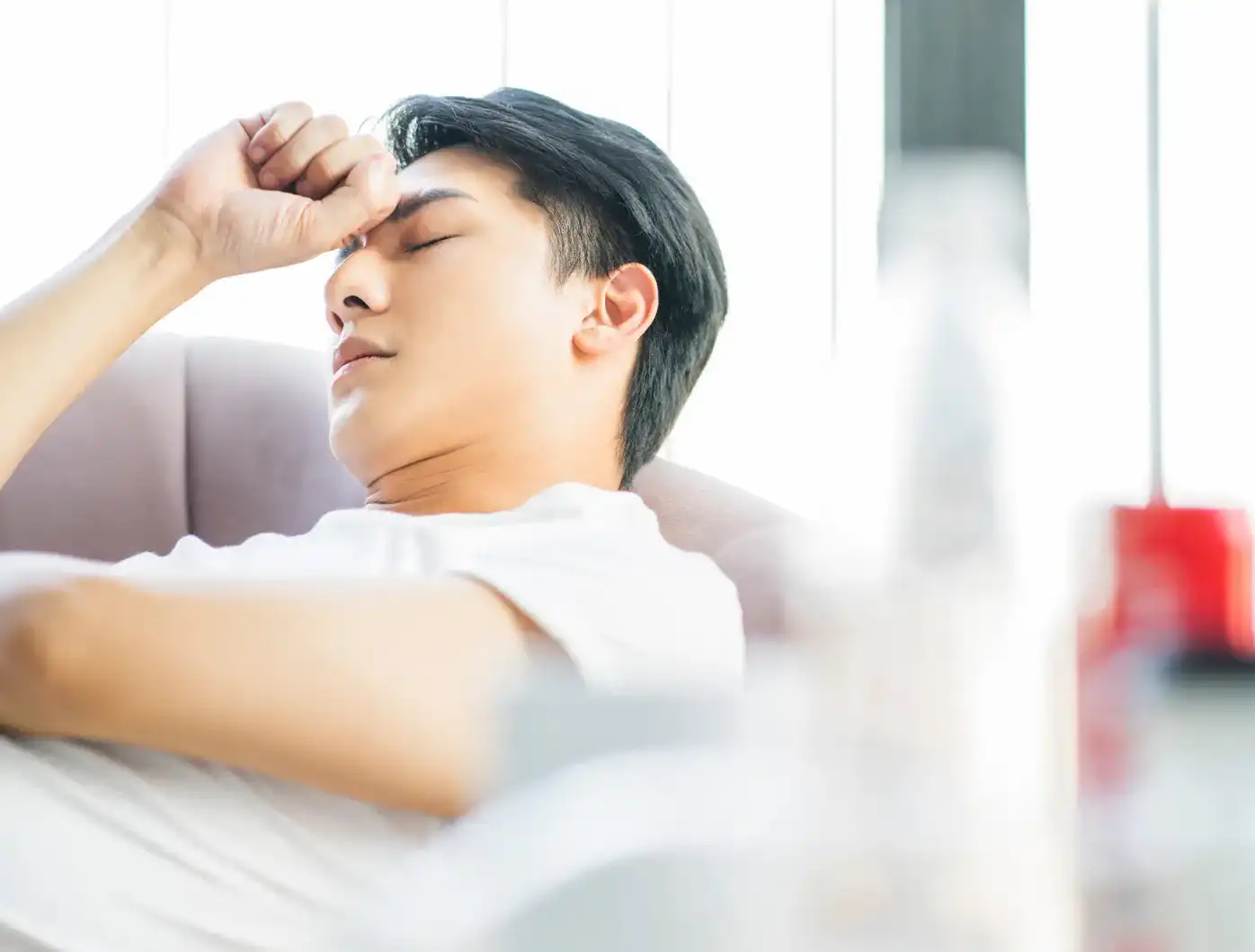 額に手を当てて横になっている男性のイメージ