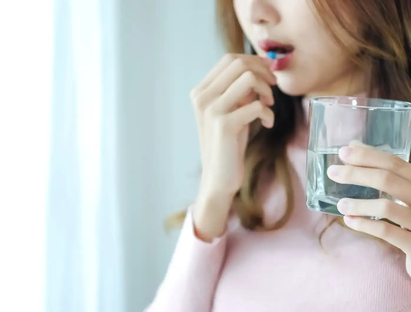 水と一緒に薬を飲む女性のイメージ